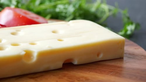 Sliced Cheese with Holes on a Chopping Board on Table
