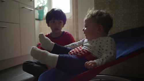 Boy with Baby Brother Sitting Indoors Relaxing