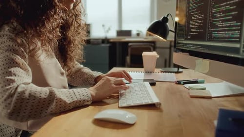 Female Developer Typing Code on Computer at Desk in Office