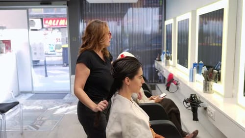 Hairdresser Brushing Woman's Long Hair in Beauty Salon