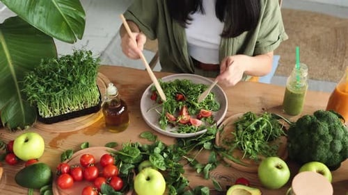 Close Up Hands of Woman Stirs Fresh Healthy Vegan Salad with Fresh Organic Vegetables