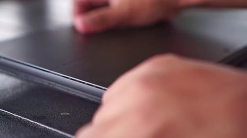 Person placing tablet on black desk, close-up detail, digital device, minimal office setup.