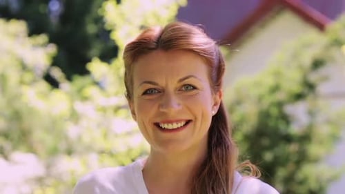 Smiling Woman with Red Hair in Green Garden