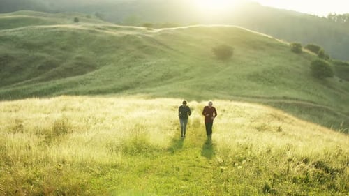 Senior Sporty Couple Running on Meadow Outdoors in Nature at Sunrise