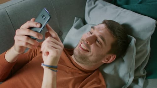Man Relaxing on Sofa Using Mobile Phone