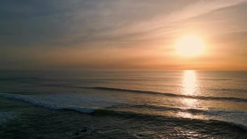 Golden sunrise light reflecting on serene ocean waves at peaceful beach