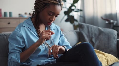 Woman checking notifications on smartwatch in living room