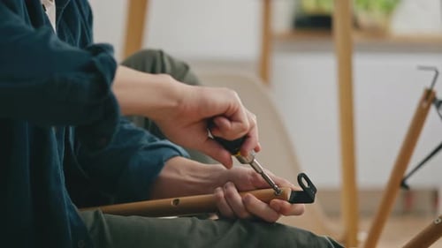 Man Assembling Furniture with Screwdriver in Home