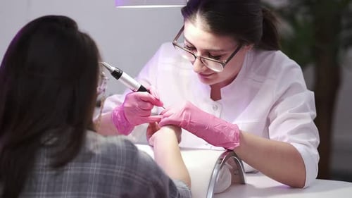 Beautician Files Client's Nails in Nail Salon