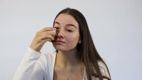 Woman Applying Foundation with Cosmetic Sponge in Studio