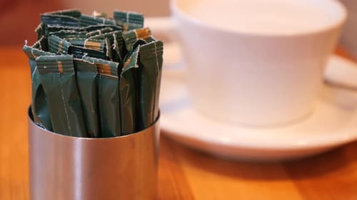 Enjoying Coffee with Sweeteners in a Cozy Cafe Setting
