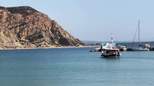 Boat sails near lighthouse in sea on sunny day