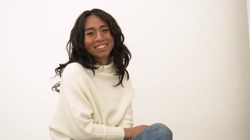 Happy young transgender woman laughing and smiling in a bright studio portrait