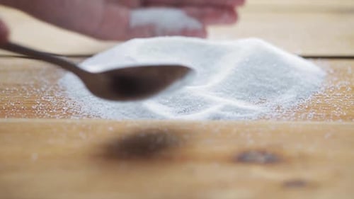 Weiße Zuckerkaskade, die einen Haufen auf dem Holztisch in einer heimischen Küche versüßt