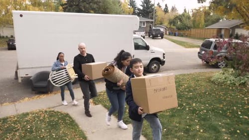 Family Moving Furniture Into House From Truck