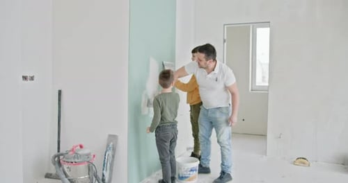 Man Teaches Boys Plastering a Wall Indoors