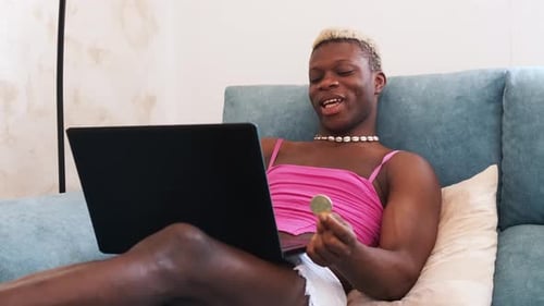 Amazed Transsexual Black Person Trading on Cryptocurrency Market in the Couch at Home