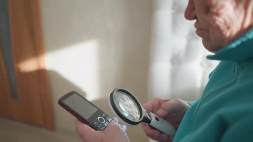 Senior Man Using Magnifying Glass with Mobile Phone