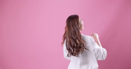 Smiling Young Woman Dancing Against Pink Background
