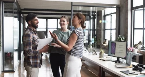 Three business professionals are engaged in a discussion in a modern office setting