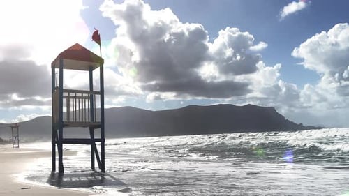 Lifeguard tower with no lifesaver on the resort coast. Waves rolling in on the sandy shore.