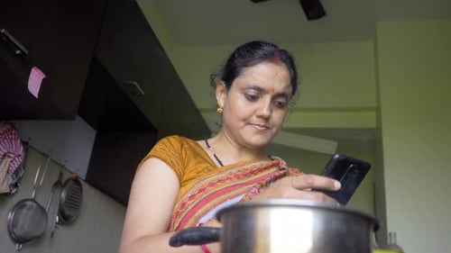 Woman Using Smartphone in Kitchen at Home