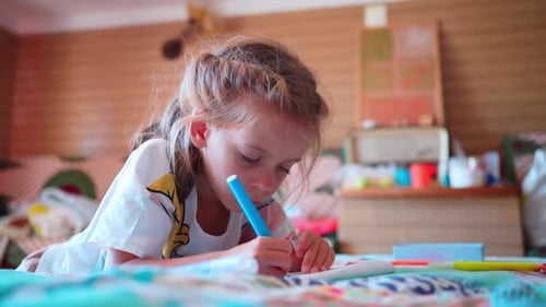 Niña pequeña dibuja o escribe en un diario con lápiz