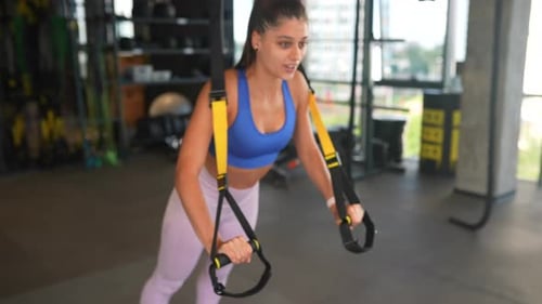 Young Athletic Woman Doing Exercises with Trx Fitness Straps in the Gym