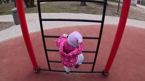Little Girl Climbing On The Ladder In The Playground. - high angle shot