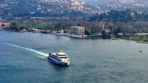 Drohnenaufnahme eines Passagierboots, das am Küçüksu-Pavillon am Bosporus vorbeifährt