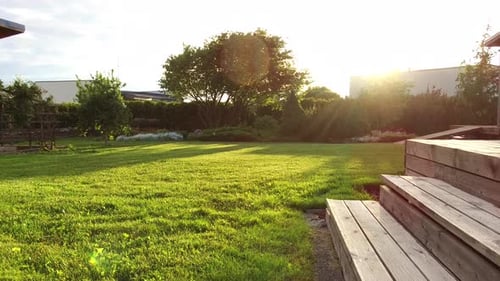 Sun shining on summer garden lawn and wooden terrace stairs in natural light