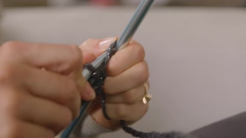 Woman knitting with grey wool. Close up.