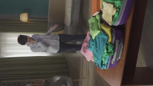 Vertical Video of a Brunette Middleaged Woman Having a Call on the Background While Packing a