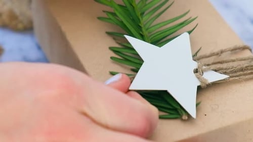 Woman Making Box with New Year's Gifts Wrapped in Craft Paper and Decorated with Fir Branch