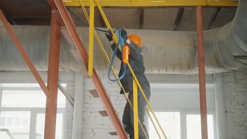 Construction or Factory Worker with Safety Gear Climbs Ladder Stairs