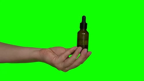 Female Hands Testing Natural Oil Cosmetics on a Chroma Green Screen Background Dropper Glass Bottle