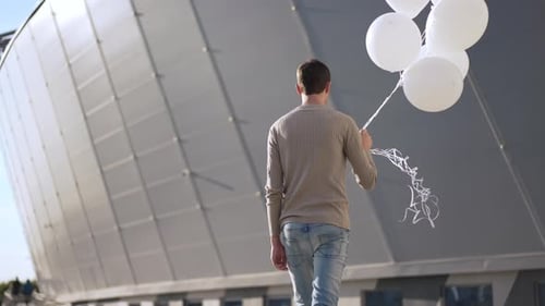 Man Walking with Balloons in an Urban Setting