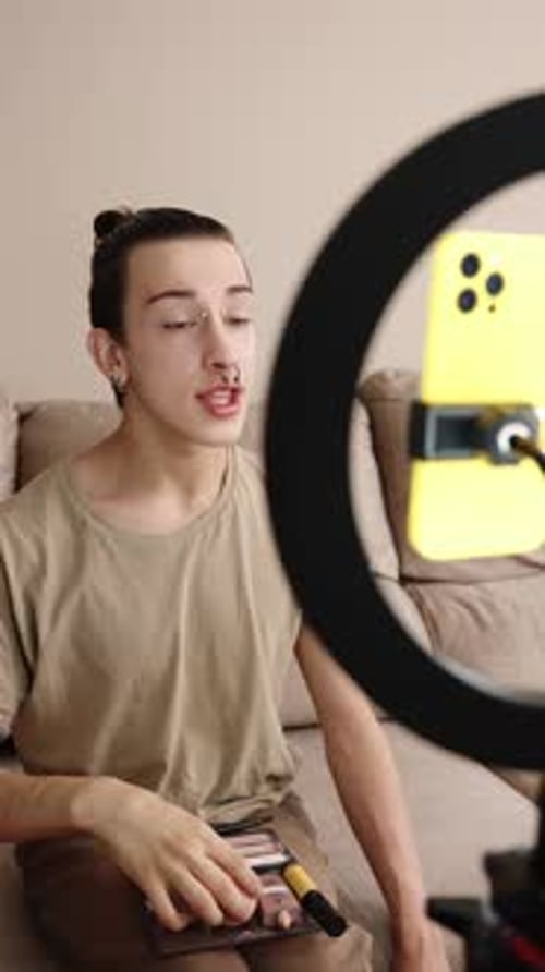 Joven influencer gay mostrando Pinceles de maquillaje y consejos con el público