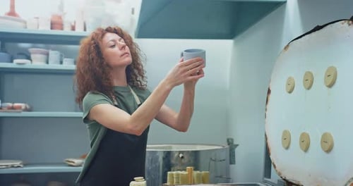 Woman Inspecting Ceramic Cup in Pottery Studio