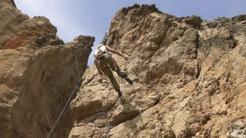Adult Female Rock Climber Descends From a Cliff on a Rope Rock Climbing