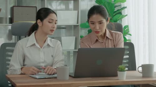 Deux jeunes femmes d'affaires enthousiastes travaillent ensemble dans l'espace de travail du bureau.