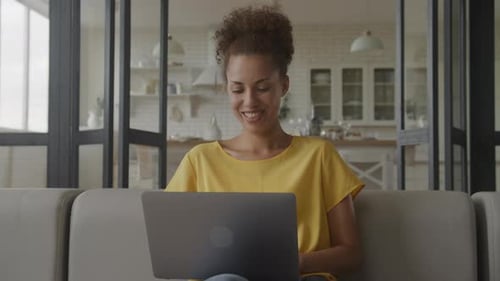 Close Up of an African American Woman Smile and Laugh While Working on Her Laptop Computer