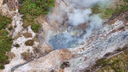 Drone footage showing a steaming sulfur vent in a volcanic landscape,