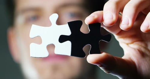 Hand Holding Black and White Puzzle Pieces