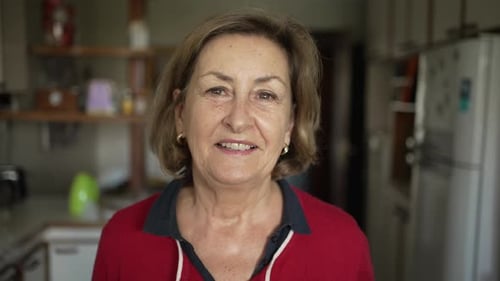 Elegant Mature Woman with Blonde Hair and Green Eyes, Wearing Red Shirt and Earrings, Smiling