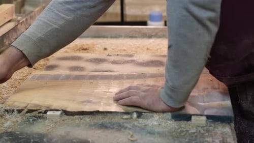 A Woodworker's Hand Dusts Off Shavings on a Freshly Cut Board Captures the Meticulous Cleanup in