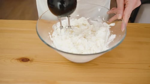 Hand Mixer Blending White Contents in Clear Bowl