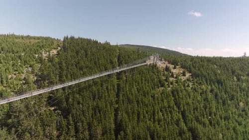 Suspended bridge leading across the valley. Sky bridge with passing visitors at high altitude. The C