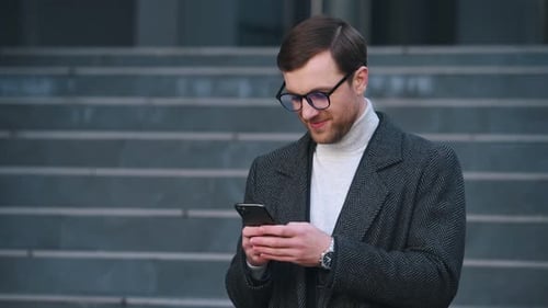 Man Using Phone Smiling in front of Building