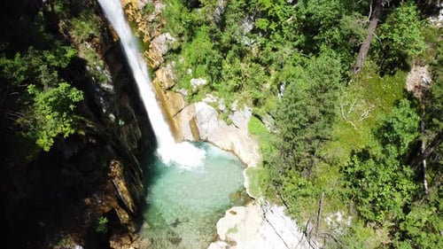 Waterfall in a mountain forest captured with drone on a sunny summer day